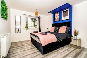 A bedroom with a bed, a window, a radiator, and a wall-mounted plant.