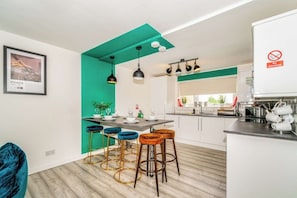 A modern kitchen with bar stools, a dining table, and a 'No smoking' sign.
