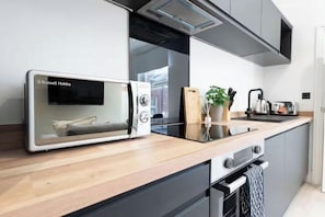 A modern kitchen with a built-in microwave, a toaster, and a coffee maker on the countertop. - Stylish Leeds Retreat | 1BR with Parking (Leeds)