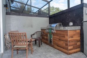Ein Außenbereich mit Küche, Grill, Holzstühlen und einem Tisch.