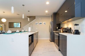 A modern kitchen with a central island, stainless steel appliances, and pendant lighting. - 4BR Le Reve Townhome Pool & Themed Rooms (Kissimmee)