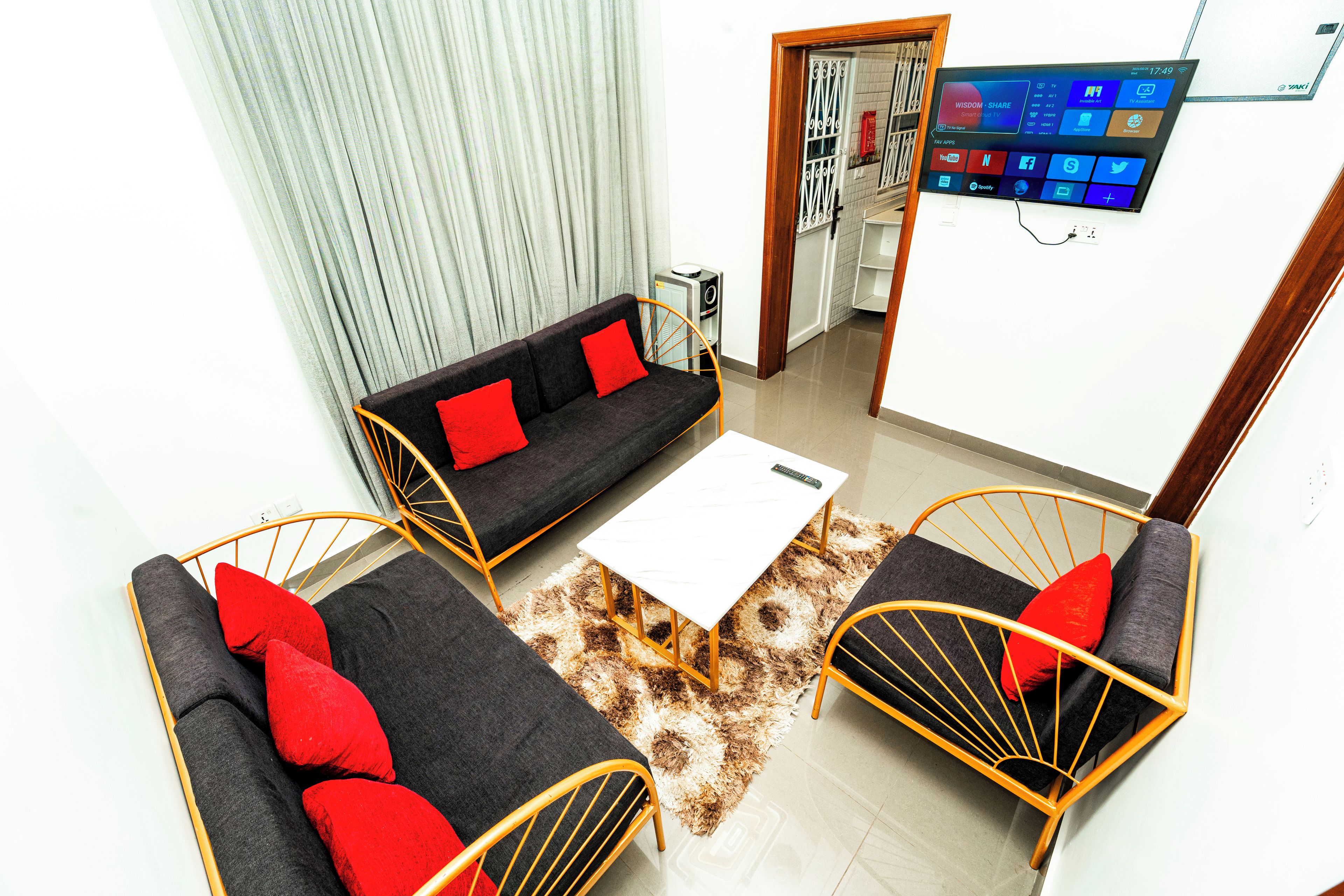 Una sala moderna con un sofá, dos sillones, una mesa de centro y un televisor de pantalla plana montado en la pared.