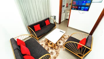 Una sala moderna con un sofá, dos sillones, una mesa de centro y un televisor de pantalla plana montado en la pared.