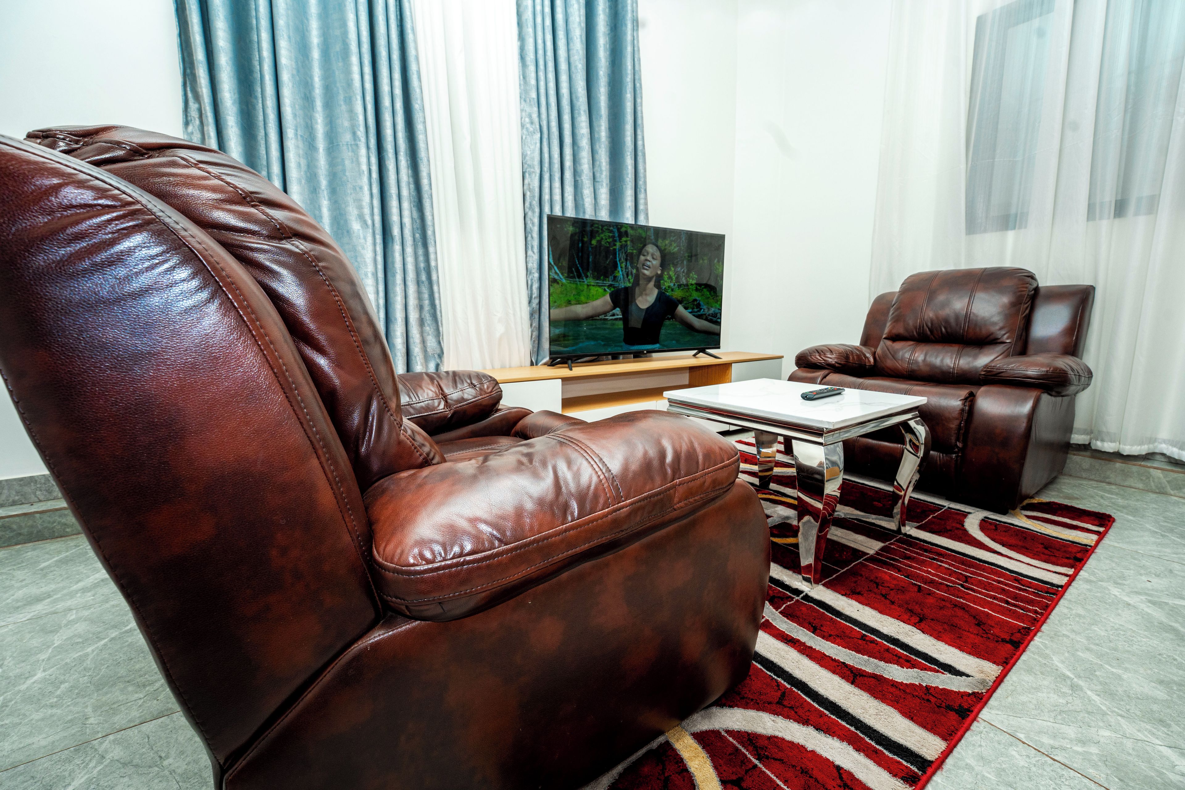 A living room with two leather sofas, a flat-screen TV, and a patterned rug.