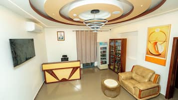 Un vestíbulo moderno con mostrador de recepción, zona de estar y techo decorativo.