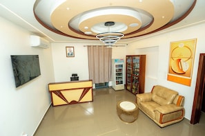 Un vestíbulo moderno con mostrador de recepción, zona de estar y techo decorativo.