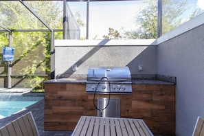 Ein Grillbereich im Freien mit Pool und Holzterrasse.