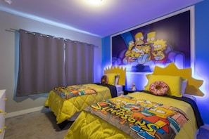 Ein Schlafzimmer mit zwei Betten, einem großen Wandgemälde zum Thema Die Simpsons und einem Fenster mit Vorhängen.