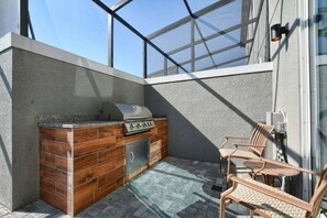 Ein Außenbereich mit einer Küche, einem Grill, Holzschränken und Sitzgelegenheiten.
