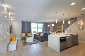 A modern kitchen with a central island, a dining area with a sofa and chairs, and a living room with a couch and a coffee table. - 4BR Themed Townhouse Pool Near Disney (Kissimmee)