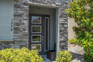 A stone facade with a dark-colored door, a mailbox, and a small garden area with shrubs. - 4BR Townhome Near Disney Pool & Mickey Room (Kissimmee)