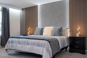 Een moderne slaapkamer met een bed, nachtkastjes en gordijnen.