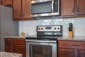 A kitchen with a stainless steel microwave, an oven, and a granite countertop. - 4BR Townhome Near Disney Pool & Mickey Room (Kissimmee)