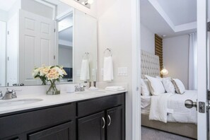 A modern bathroom with a large mirror, two sinks, and a vase of flowers. - 5BR Solara Home Private Pool & Themed Rooms (Kissimmee)