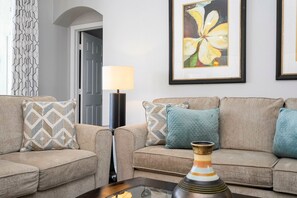 A living room with a sofa set, patterned cushions, a floor lamp, and a framed painting on the wall. - 4BR Windsor Palms Pool, spa & Mickey Room (Kissimmee)