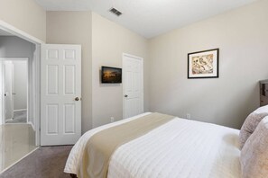 A bedroom with a bed, two doors, a picture on the wall, and a carpeted floor. - 4BR Windsor Palms Pool, spa & Mickey Room (Kissimmee)