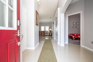 A hallway with a red door, a rug, and a bed with a Mickey Mouse blanket. - 4BR Windsor Palms Pool, spa & Mickey Room (Kissimmee)