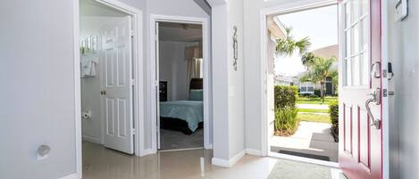 Un pasillo con una puerta roja que da a un dormitorio con una cama y un ventanal.