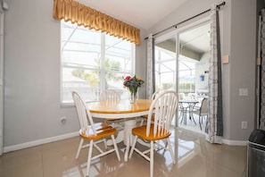 A dining area with a table and chairs, a window with blinds, and a view of the outdoors. - 4BR Windsor Palms Pool, spa & Mickey Room (Kissimmee)