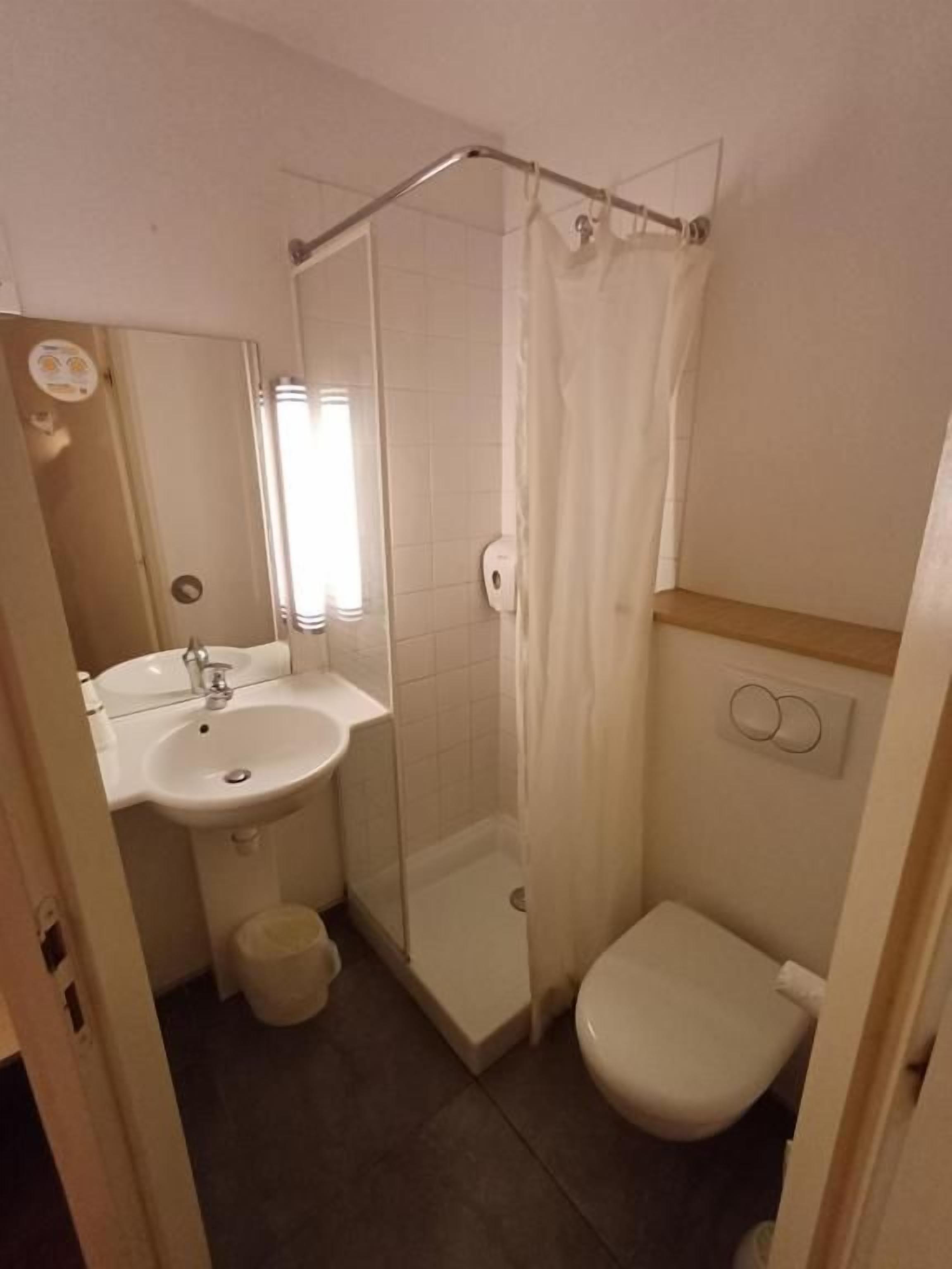 Ein Badezimmer mit Dusche, Toilette, Waschbecken und Spiegel.
