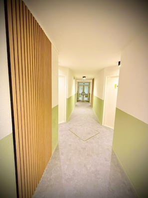Un pasillo con paneles de madera en una pared, suelo alfombrado y puertas que dan a habitaciones.