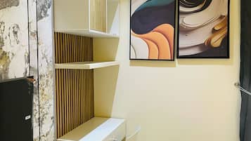 Una habitación de hotel moderna con un escritorio blanco, una silla, una cama y dos cuadros abstractos en la pared.