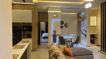 Una sala moderna con un sofá, un comedor y una cocina visible al fondo.
