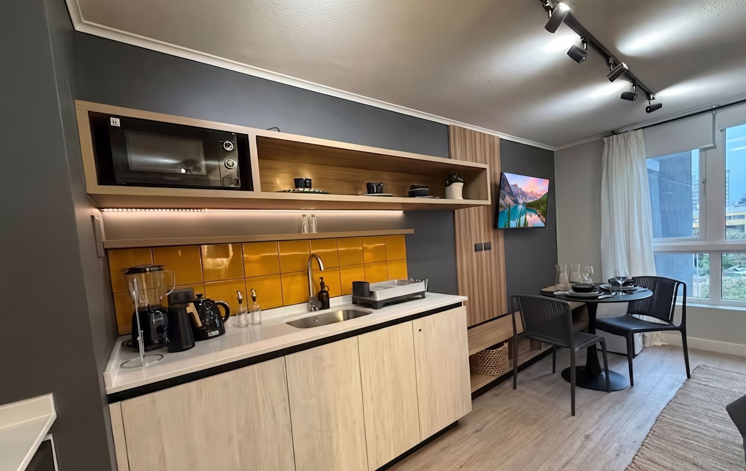 Een moderne keuken met inbouwapparatuur, een eethoek met een tafel en stoelen, en een groot raam met uitzicht.