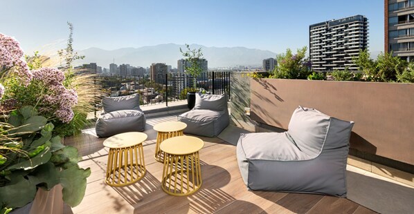 A rooftop terrace with outdoor seating, a view of the city, and mountains in the distance. - Casa Bustamante by Domus Travels (Ñuñoa)