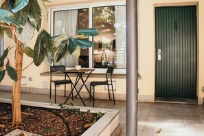 An outdoor seating area with a table and chairs, a door, and a plant. - Urban Suite - Lakeside L&b (Milano)