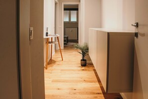 Een smalle gang met houten vloer die leidt naar een keuken met een eettafel en stoelen.