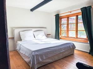 A bedroom with a bed, a window with curtains, and a radiator. - Historic Baltic Sea cottage, hot tub, sauna, fireplace (Barsbek)
