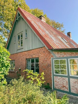A two-story house with a red roof and green siding, surrounded by greenery. - Historic Baltic Sea cottage, hot tub, sauna, fireplace (Barsbek)