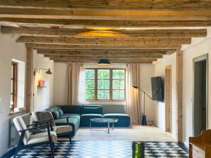 A living room with a sofa, chairs, a coffee table, a TV, and a window with curtains. - Historic Baltic Sea cottage, hot tub, sauna, fireplace (Barsbek)