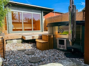 A patio area with a wooden deck, a seating arrangement, and a wood-burning stove. - Historic Baltic Sea cottage, hot tub, sauna, fireplace (Barsbek)