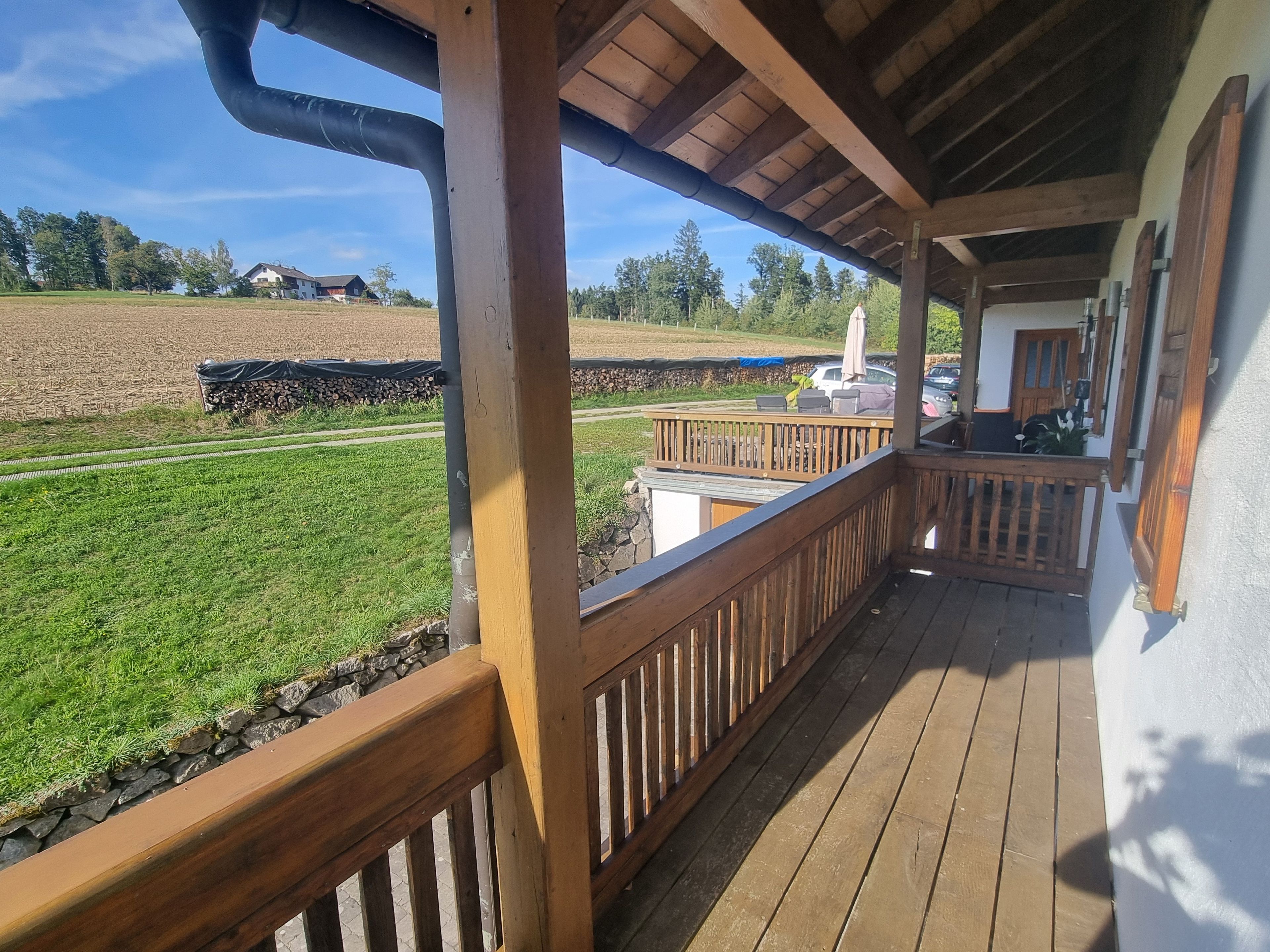 Eine Holzterrasse mit Blick auf ein Feld und ein Gebäude in der Ferne.