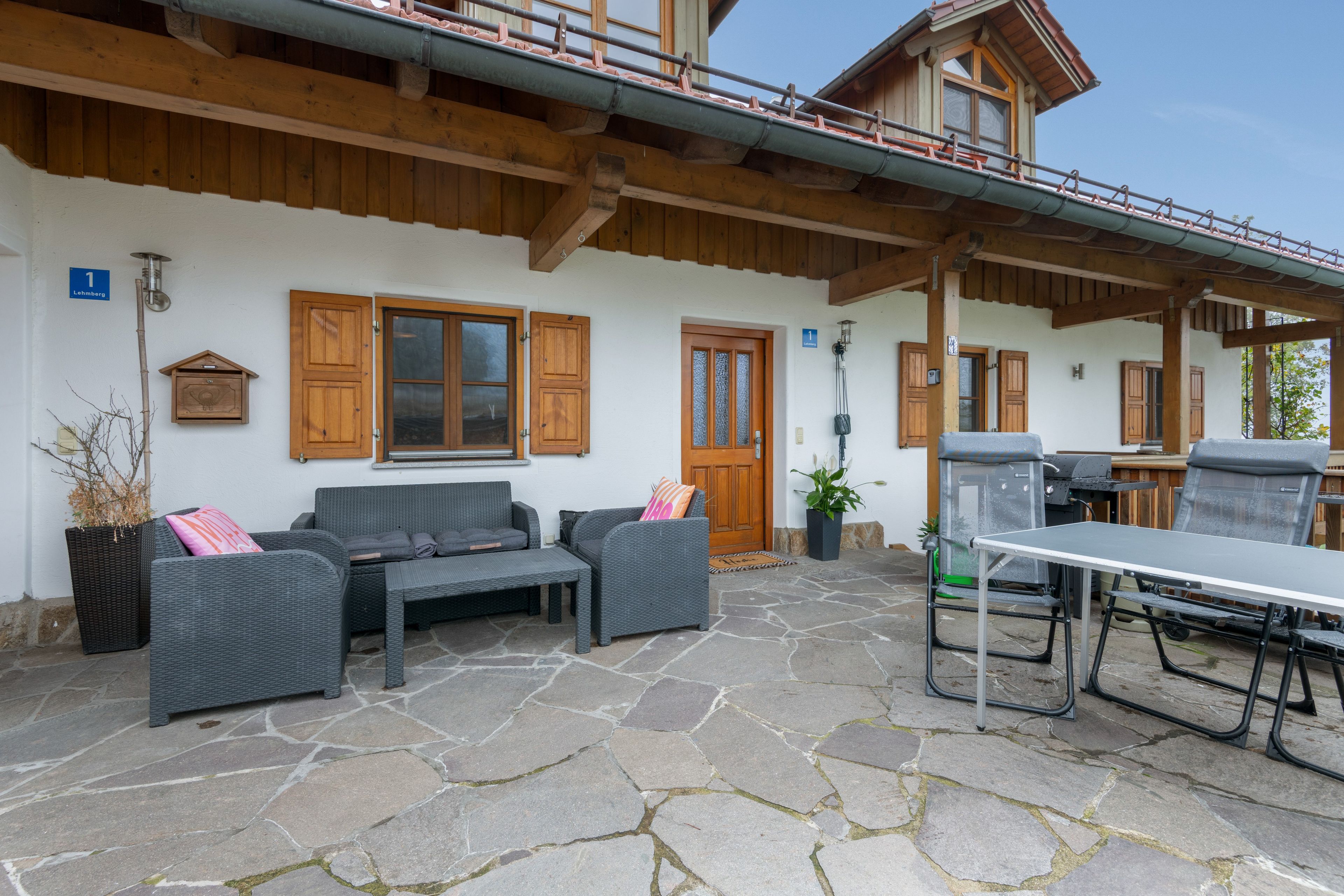Un patio in pietra con mobili da esterno, una porta in legno e un piccolo balcone.
