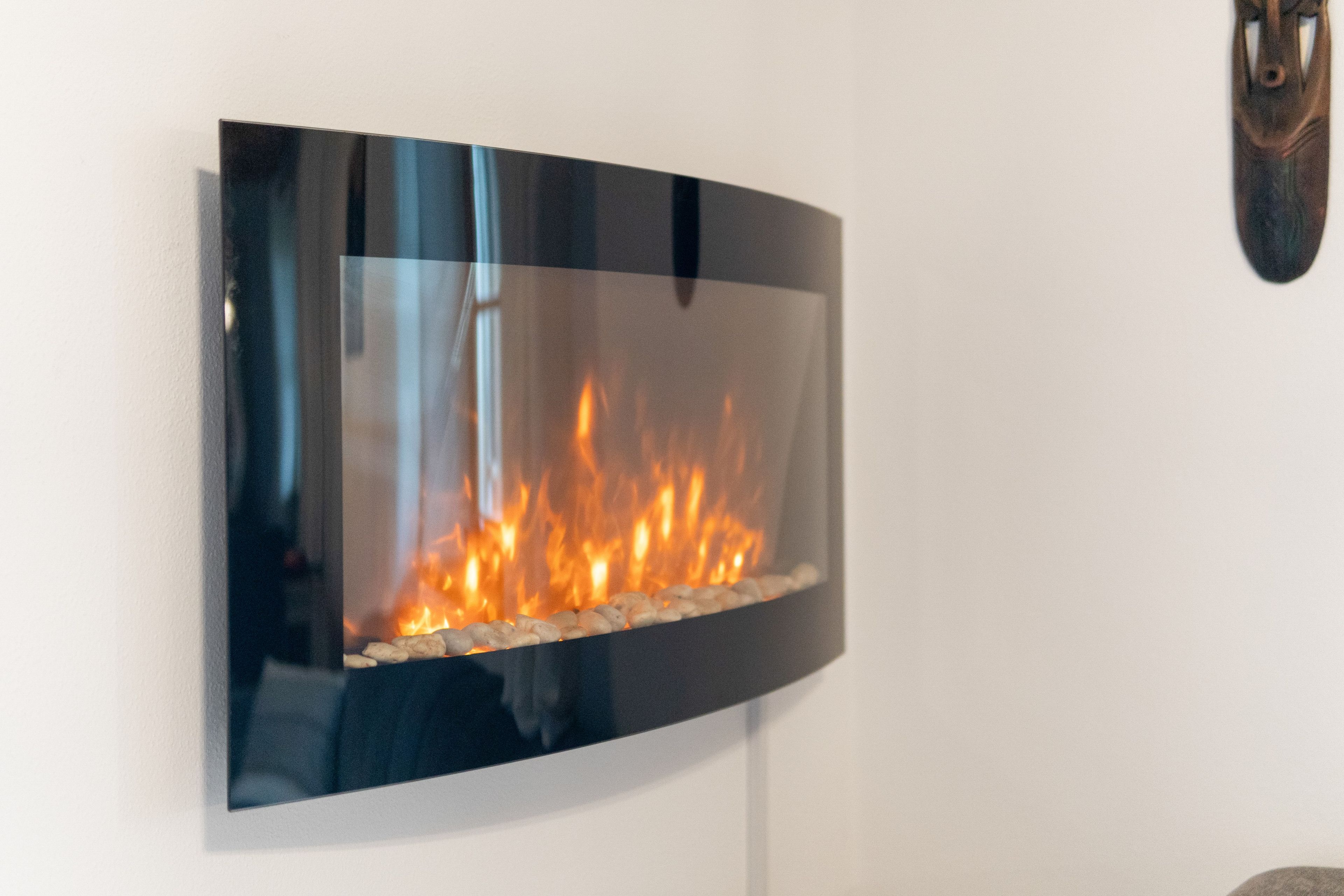 Una chimenea moderna empotrada en la pared, con frente de vidrio transparente mostrando fuego.