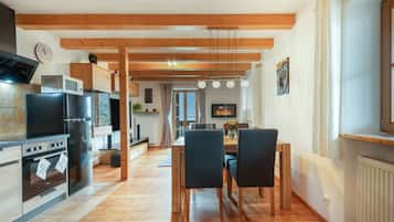 A modern kitchen with wooden beams, stainless steel appliances, and a dining area with a wooden table and chairs.