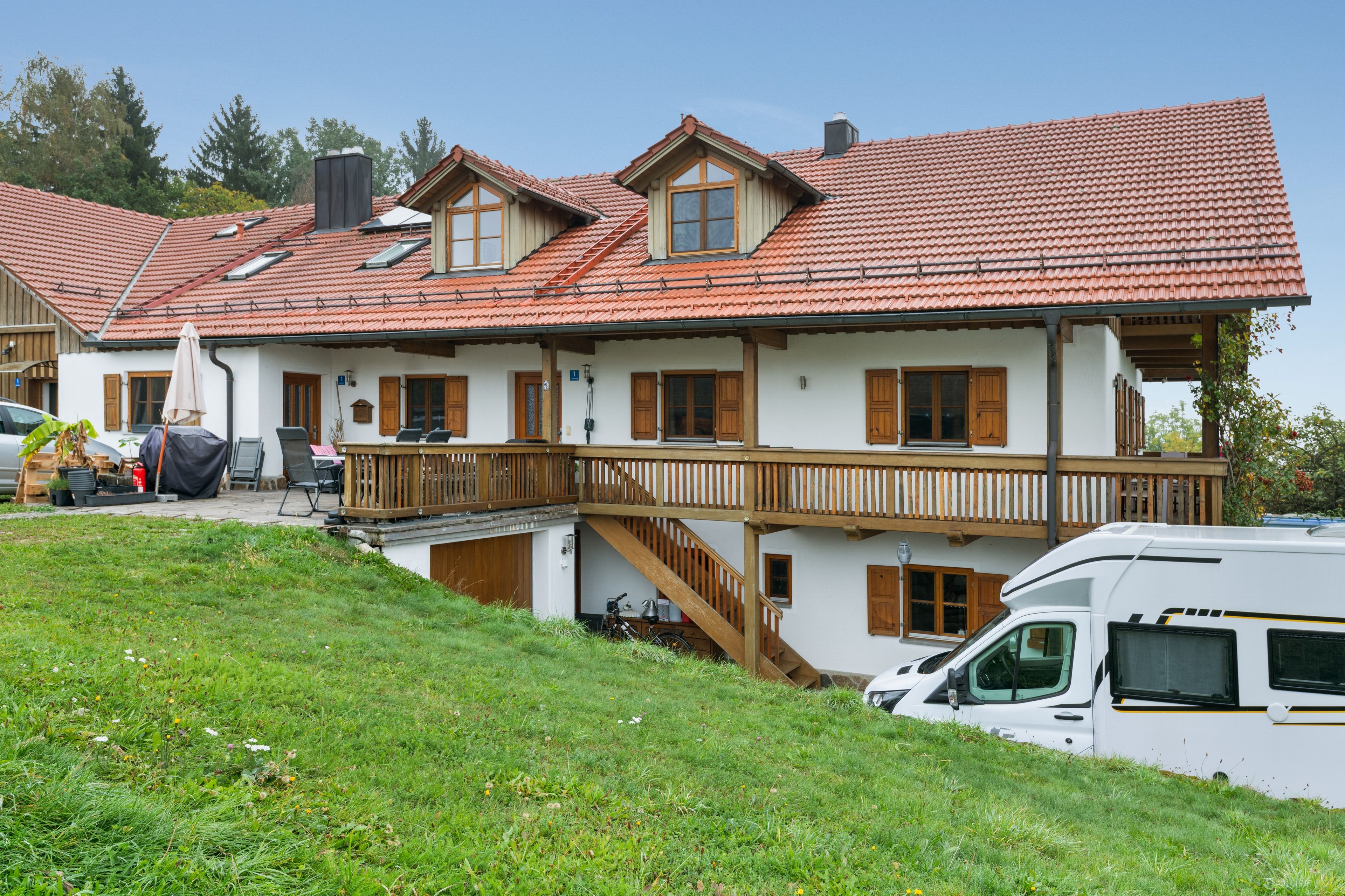 Ein zweistöckiges Haus mit rotem Ziegeldach, einem hölzernen Balkon und einer weißen Fassade.