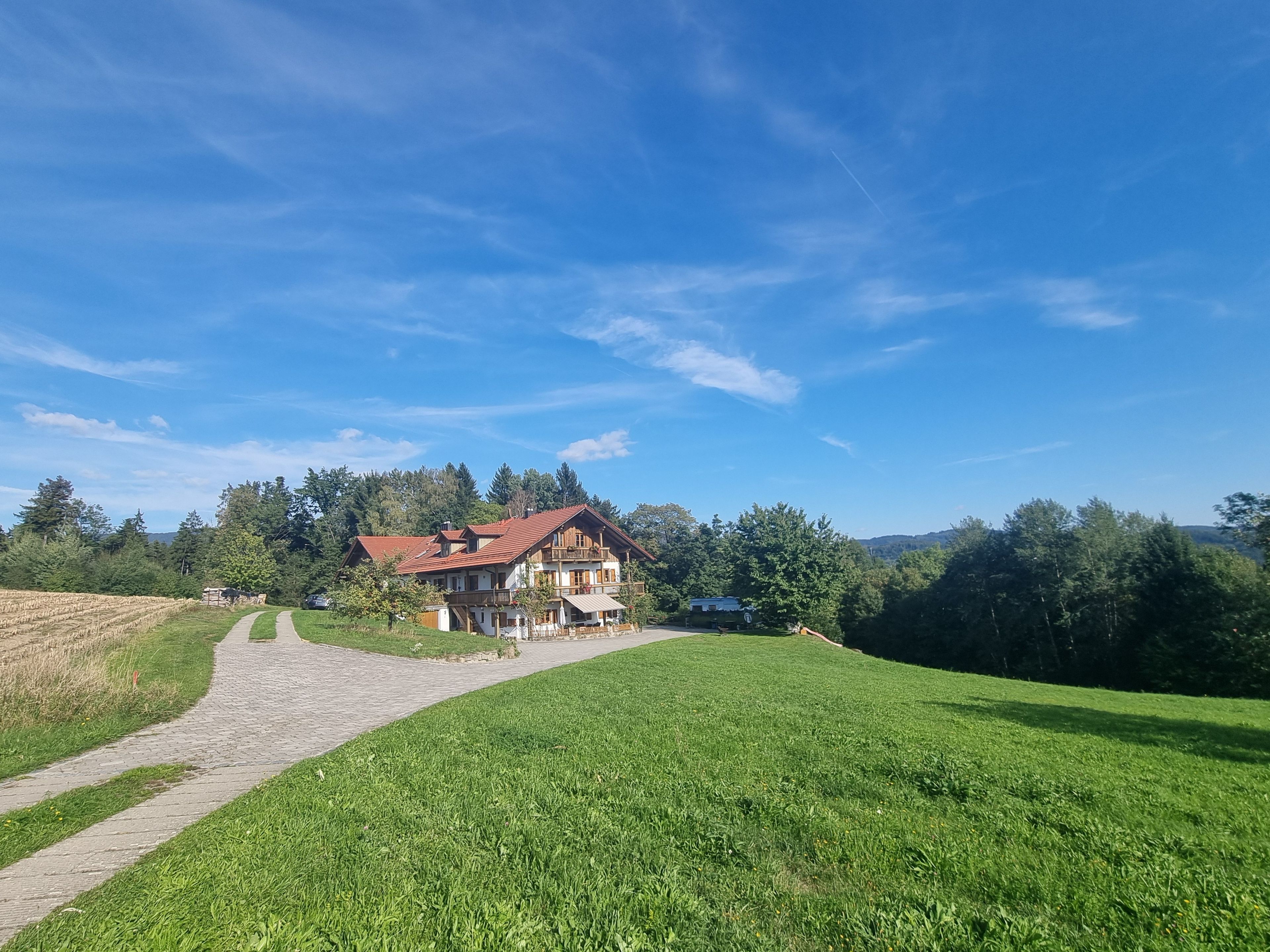 Ein zweistöckiges Haus mit rotem Dach, umgeben von einer grünen Wiese und Bäumen.