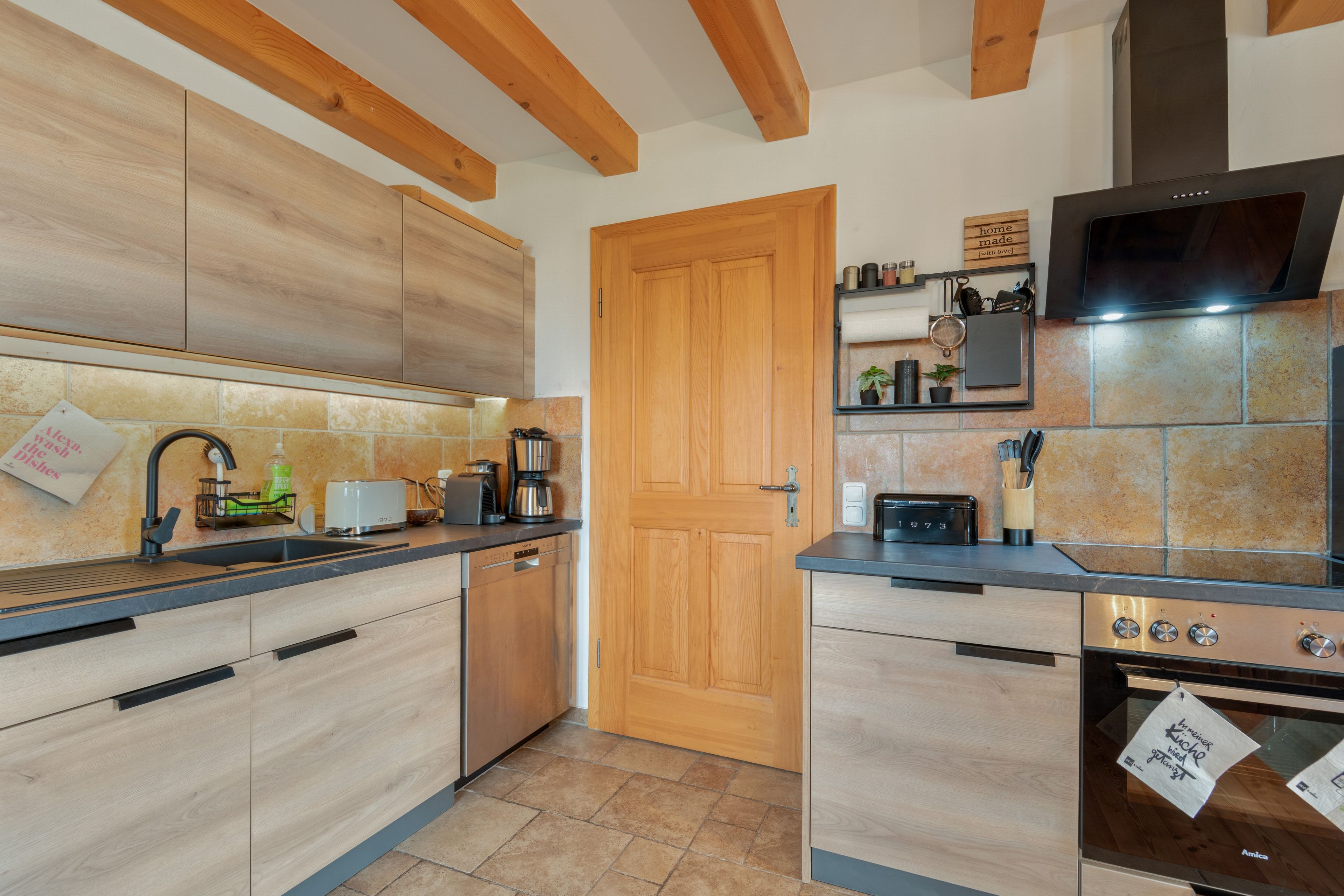 Eine moderne Küche mit Holzschränken, einem Backofen und einer Kaffeemaschine.