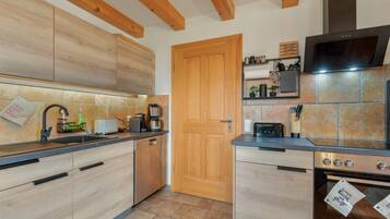 Eine moderne Küche mit Holzschränken, einem Backofen und einer Kaffeemaschine.