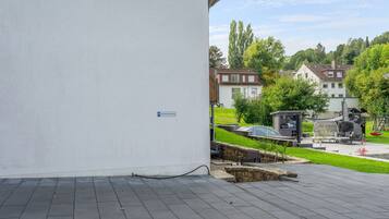 Ein gepflasterter Außenbereich mit einer Steinmauer, einer kleinen Sitzecke mit Tisch und Stühlen sowie einem Schild, das einen Parkplatz kennzeichnet.