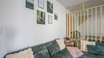 A modern living room with a green sofa, a small side table, and a wooden partition.