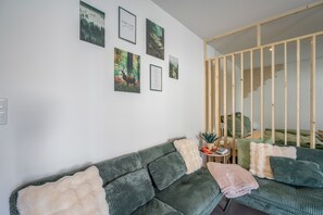 Una sala de estar moderna con un sofá verde, una mesita auxiliar y una partición de madera.