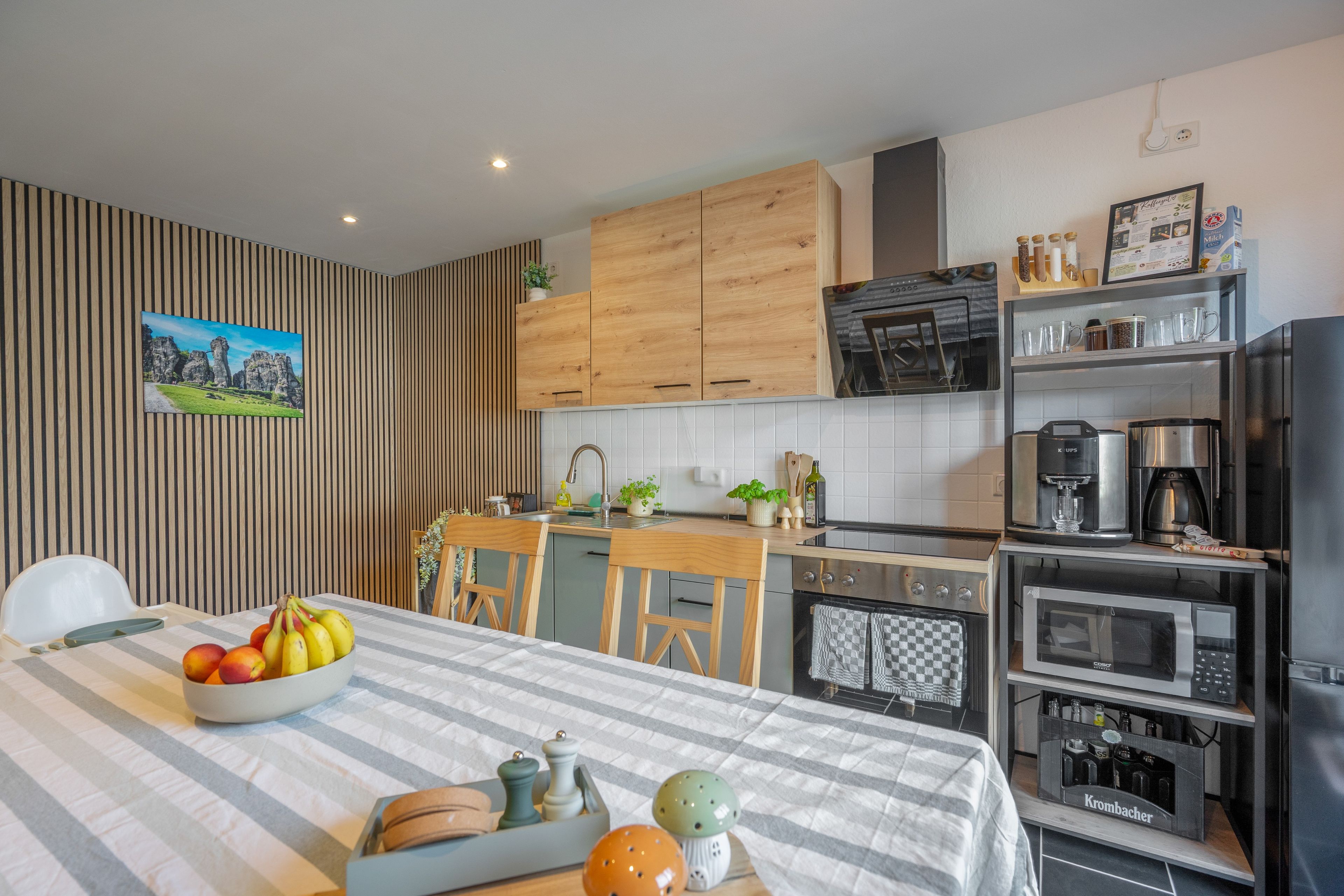 Eine moderne Küche mit Holzschränken, einem Backofen, einer Kaffeemaschine und einer Mikrowelle.