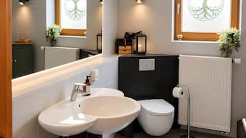 Ein modernes Badezimmer mit einem Doppelwaschbecken, Toilette und einem Fenster mit Baumdekor.