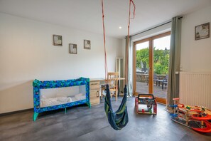 Una habitación con literas, un escritorio, una silla, una hamaca y una zona de juegos con juguetes.