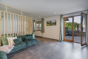 A modern living room with a sectional sofa, a glass door leading to an outdoor patio, and a painting on the wall.